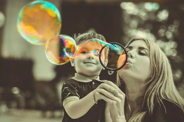 This shows a mom blowing bubbles with her son