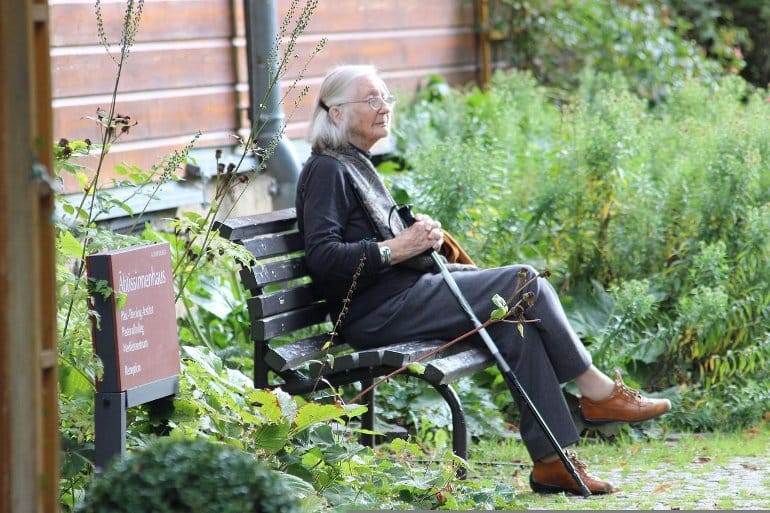 This shows an older woman sitting on a park bench