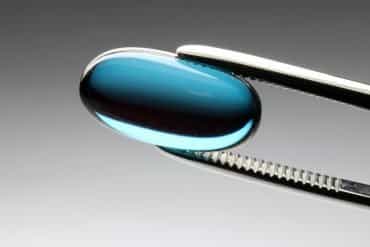 This shows a pill in a pair of tweezers