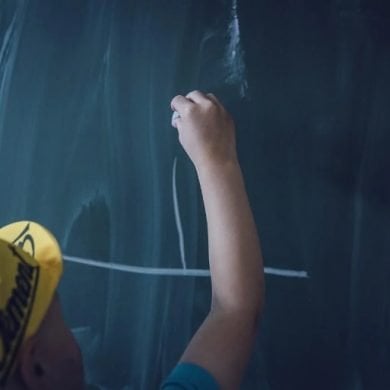 This shows a child writing on a blackboard