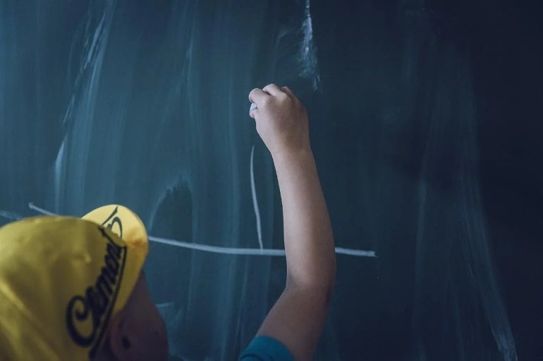This shows a child writing on a blackboard