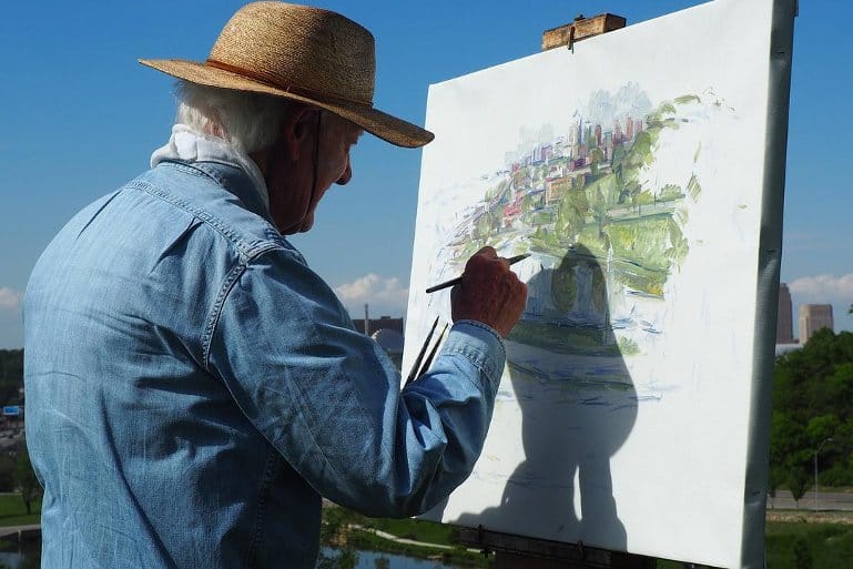 This shows an older man painting