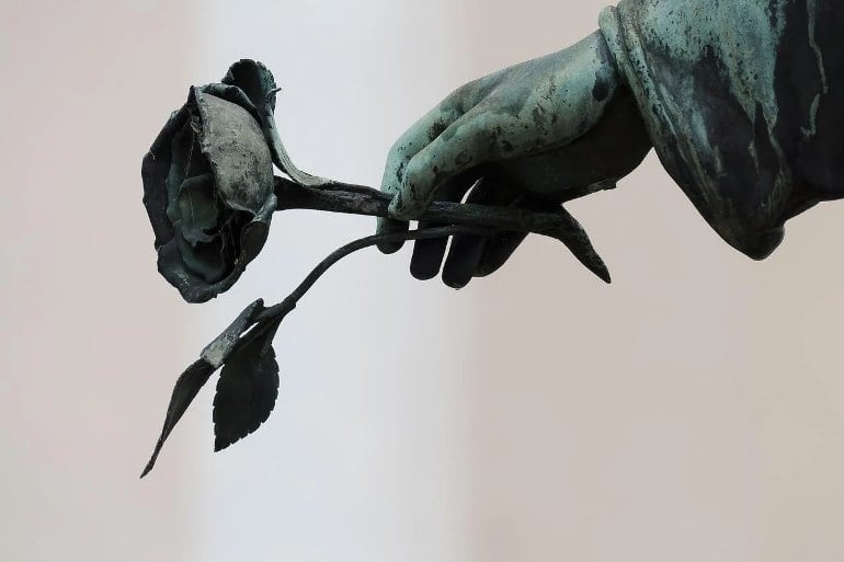 This shows a statue of a hand holding a rose