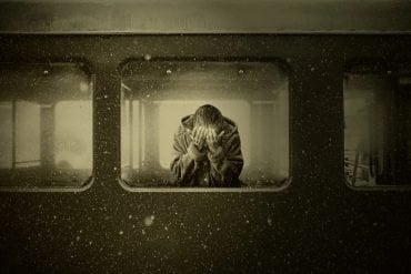 This shows an older woman crying on a train