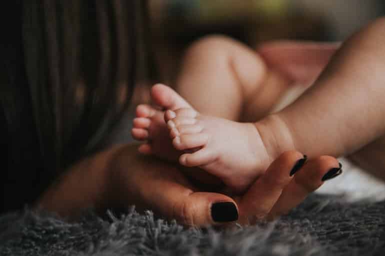 This shows a mom's hand holding a baby's feet