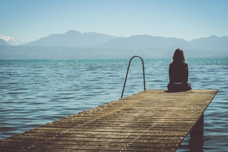 This shows a woman sitting alone on a dock