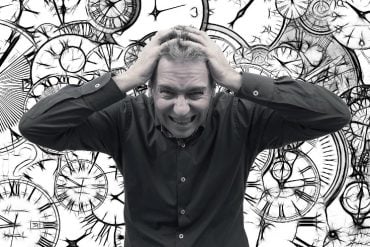 This shows a stressed looking man surrounded by clocks