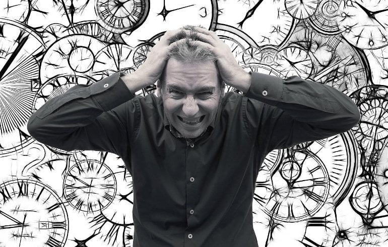 This shows a stressed looking man surrounded by clocks