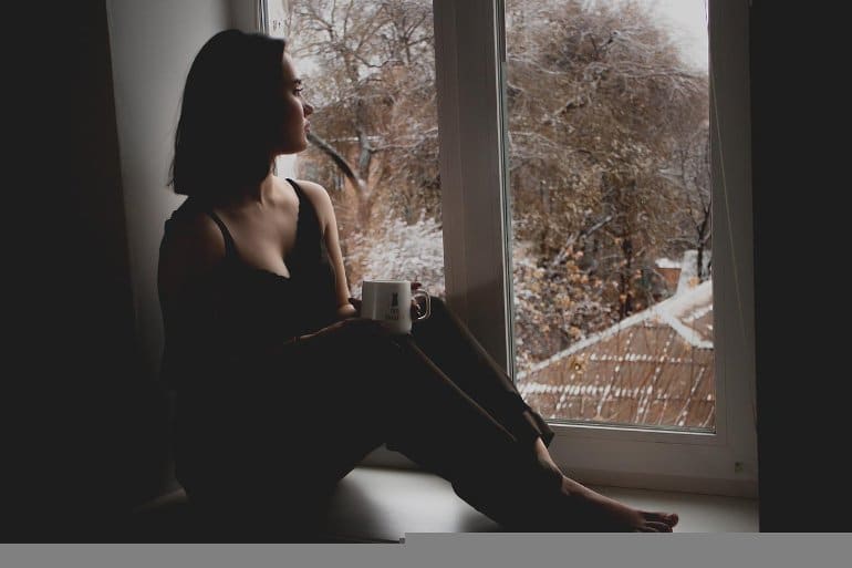 This shows a sad woman sitting at a window