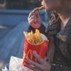 This shows a woman eating fries