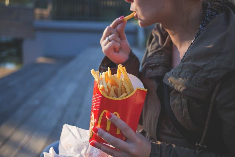 This shows a woman eating fries