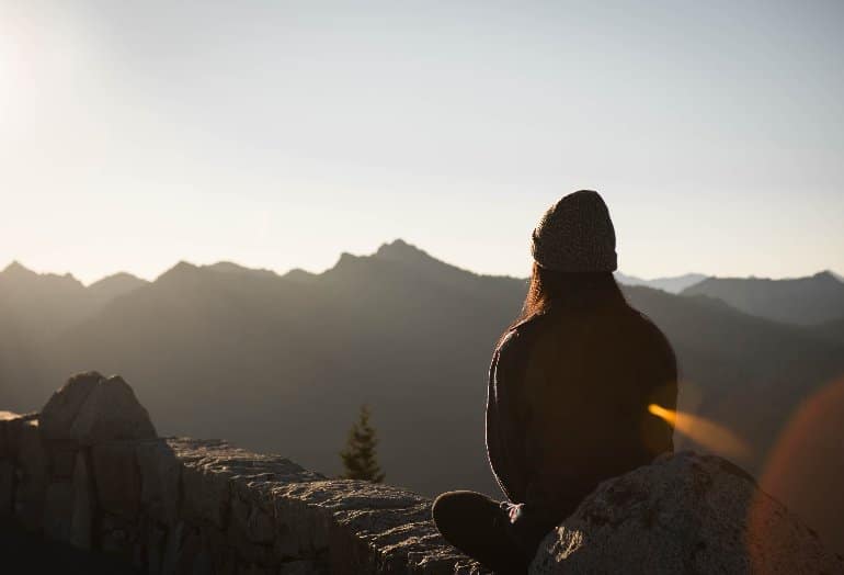 This shows a woman sitting on a hill, meditating