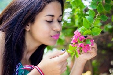 This shows a woman smelling flowers