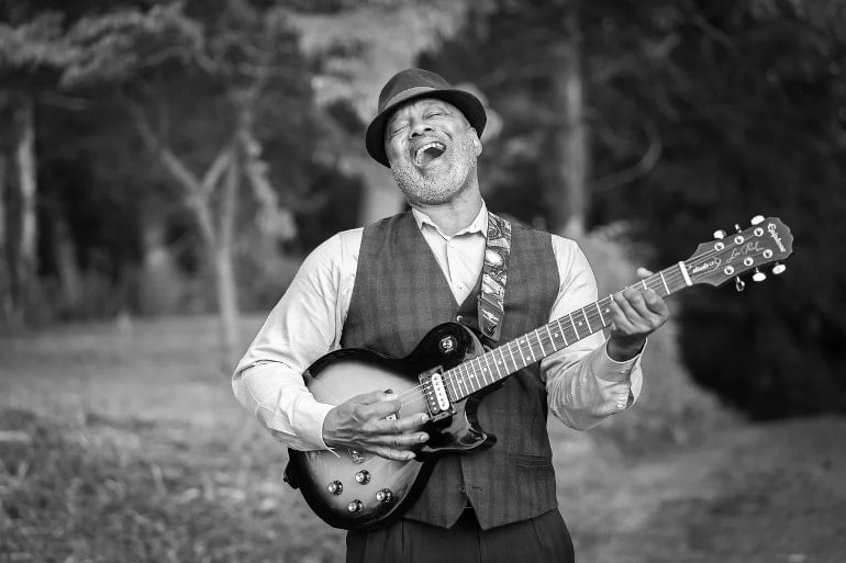 This shows an older man playing guitar and singing