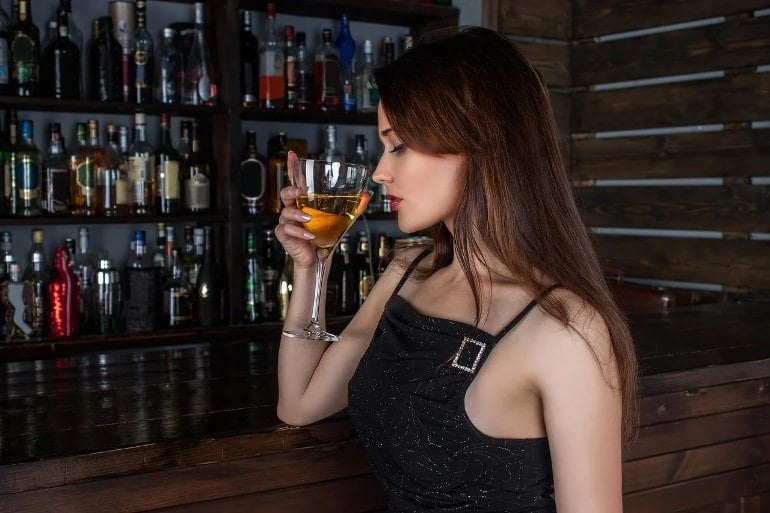 This shows a woman drinking a cocktail