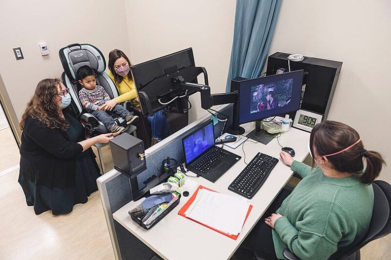 This shows a young boy with his mom and the researchers