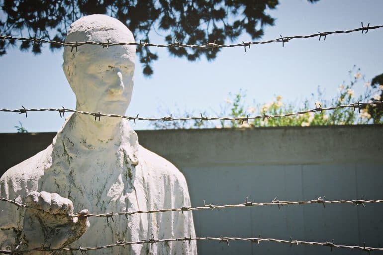 This shows a statue of a suffering man behind barbed wire