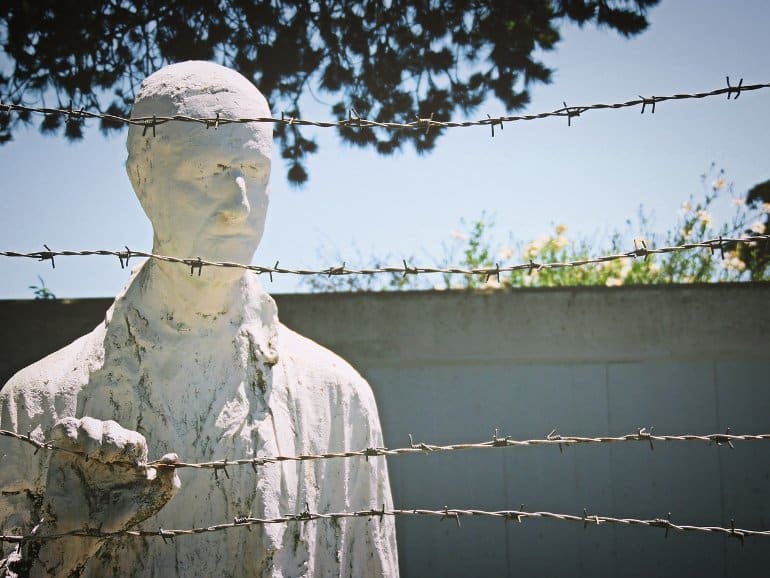 This shows a statue of a suffering man behind barbed wire