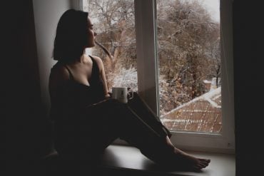This shows a sad woman sitting by a window