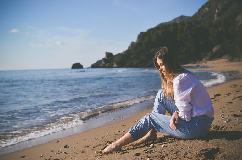 This shows a sad woman sitting on a beach