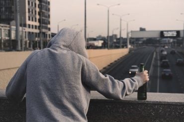 This shows a man holding a beer bottle