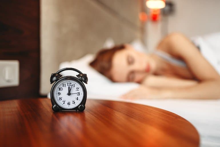 This shows an alarm clock and a woman sleeping