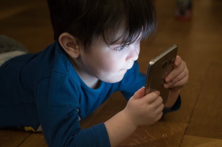 This shows a child looking at a smart phone