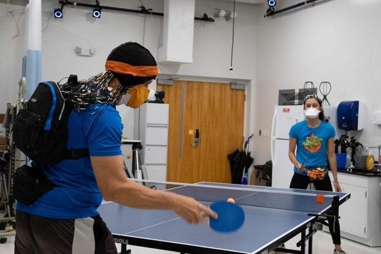 This shows a person playing table tennis against a robot