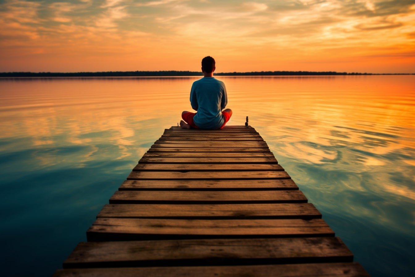 This shows a person meditating on a dock.