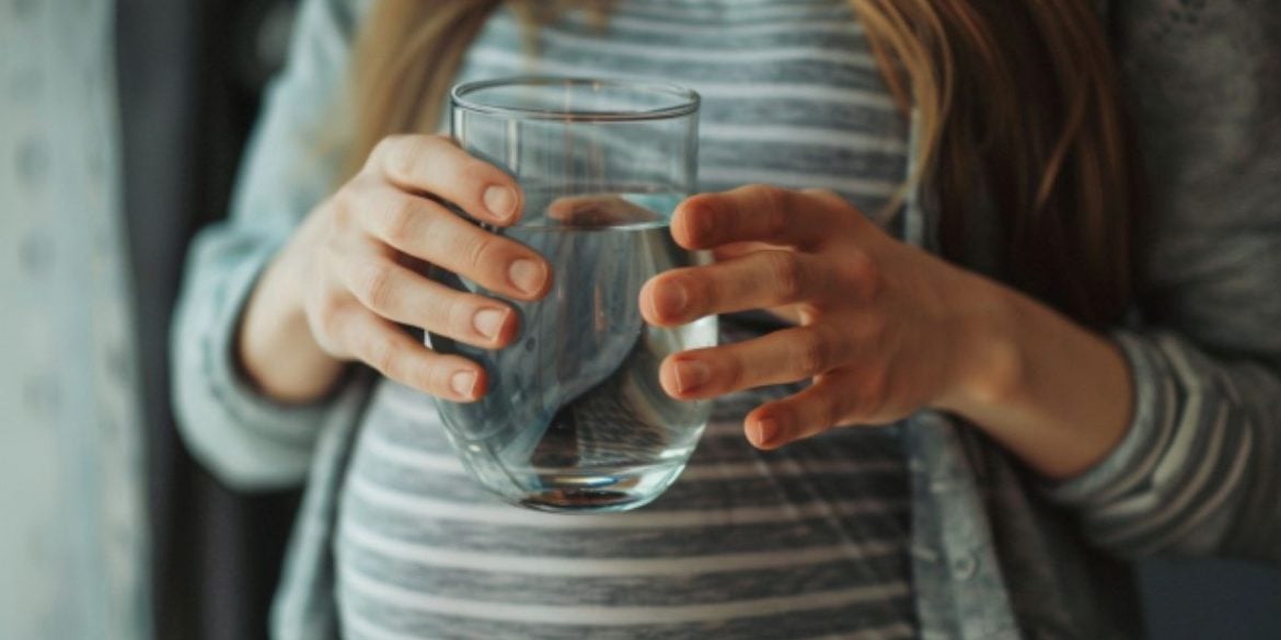 This shows a pregnant woman drinking water.