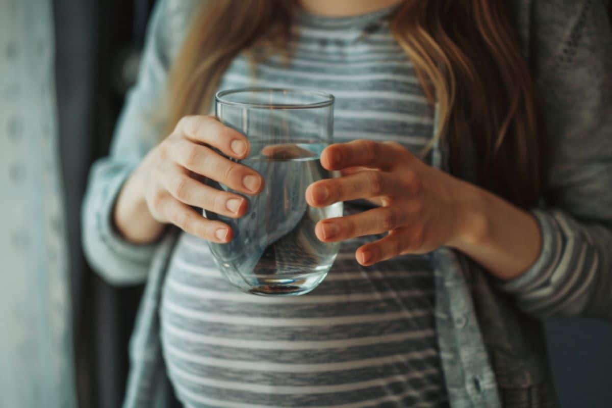 This shows a pregnant woman drinking water.