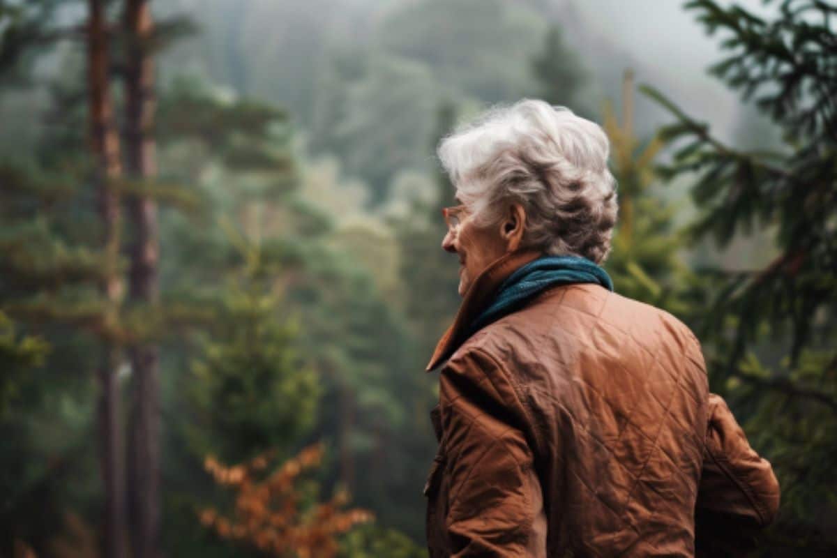 This shows an older woman walking in the woods.