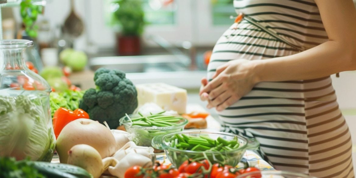 This shows a pregnant woman at a table with healthy foods.