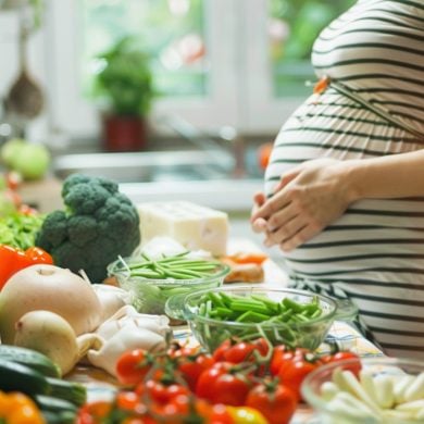 This shows a pregnant woman at a table with healthy foods.
