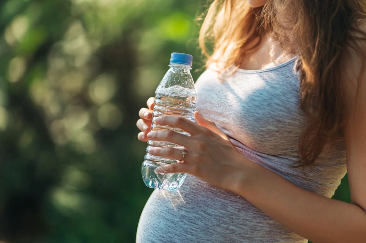 This shows a pregnant woman holding a bottle of water.