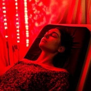 This shows a woman laying under a red light.