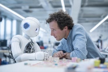This shows a man making eye contact with a robot.