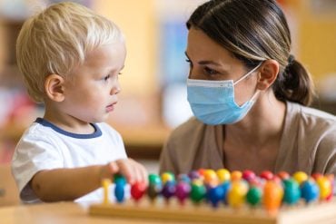 This shows a child and an adult in a surgical mask.