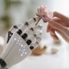 This shows a robotic hand touching a rose.