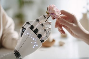 This shows a robotic hand touching a rose.