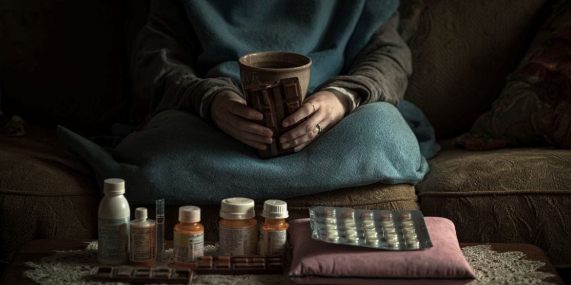 This shows a woman holding chocolate and a table with pain pills.