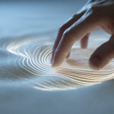 This shows a hand touching sand.