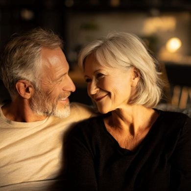 This shows an older couple hugging on a sofa.
