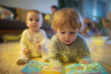This shows a toddler with a book and an infant.