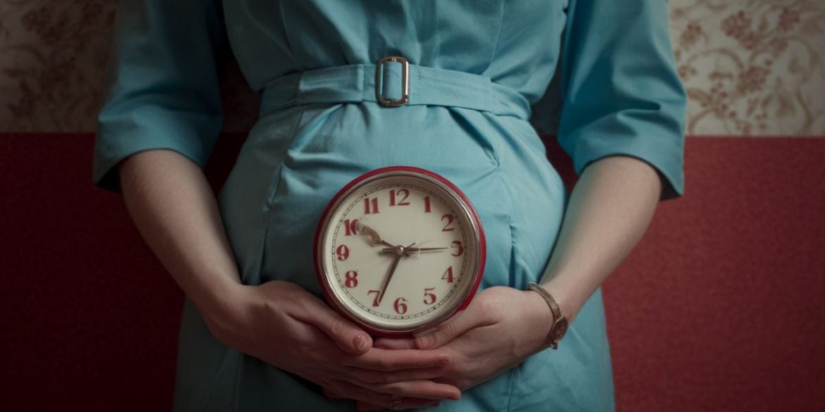 This shows a pregnant woman holding a clock.