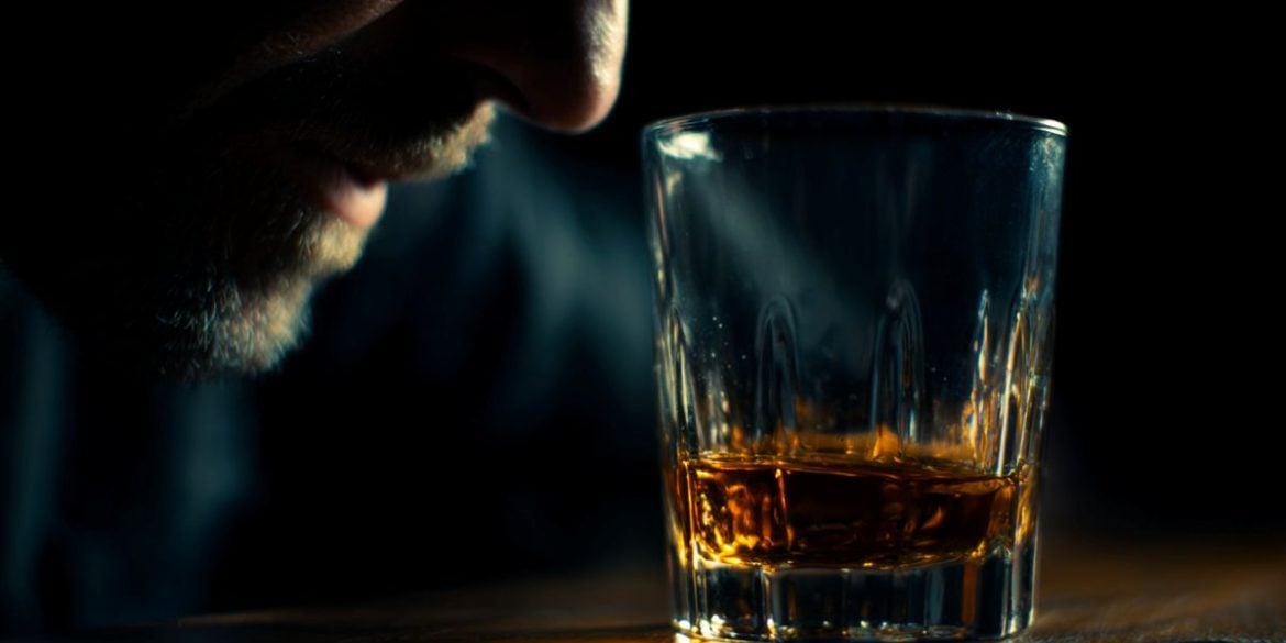 This shows a drink and a man's face with a black background.