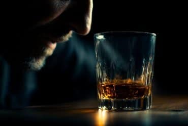 This shows a drink and a man's face with a black background.