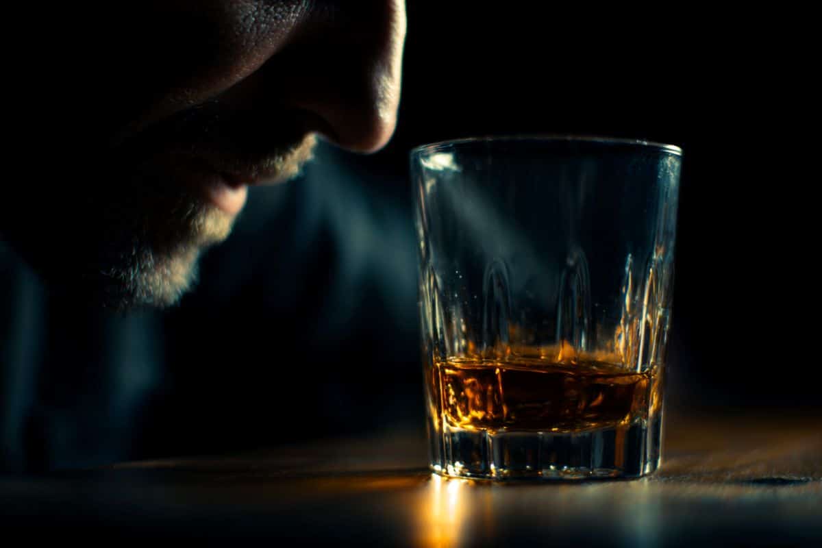 This shows a drink and a man's face with a black background.