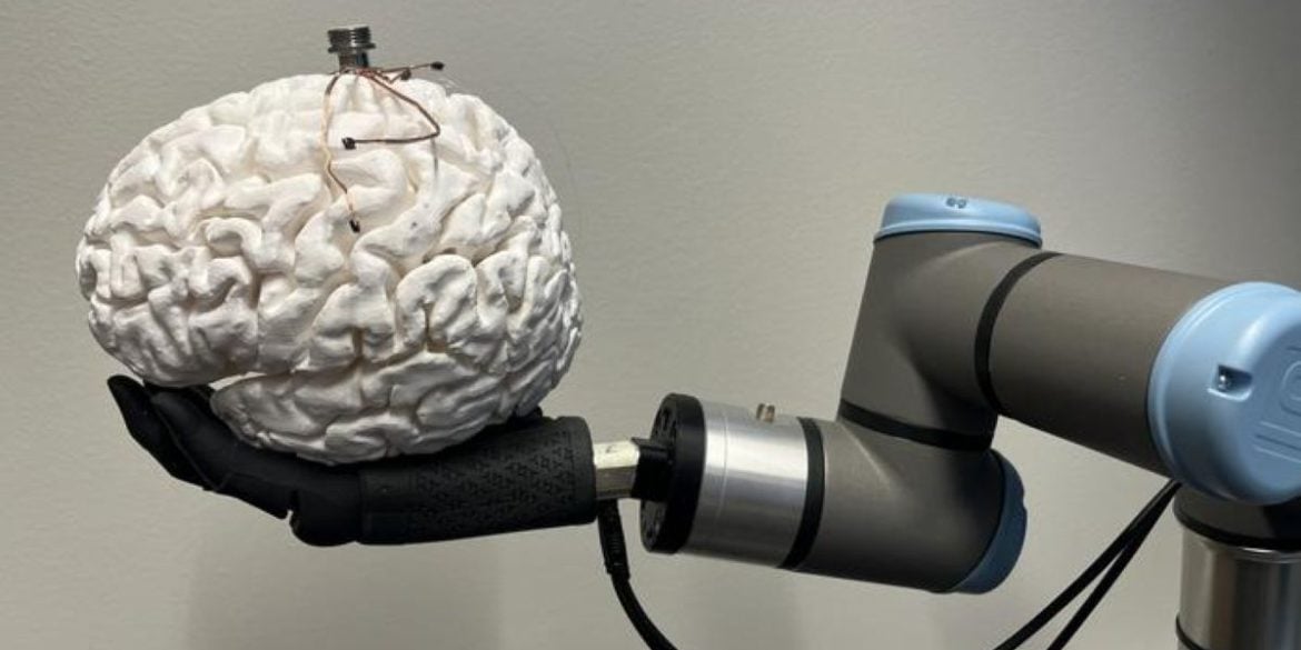 This shows a robotic hand holding a brain with the bci on top of it.