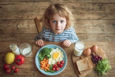 This shows a child sitting with a plate of food.